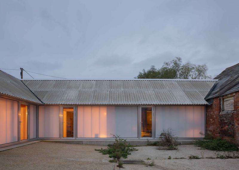 Courtyard house with polycarbonate facade, glowing in the evening.